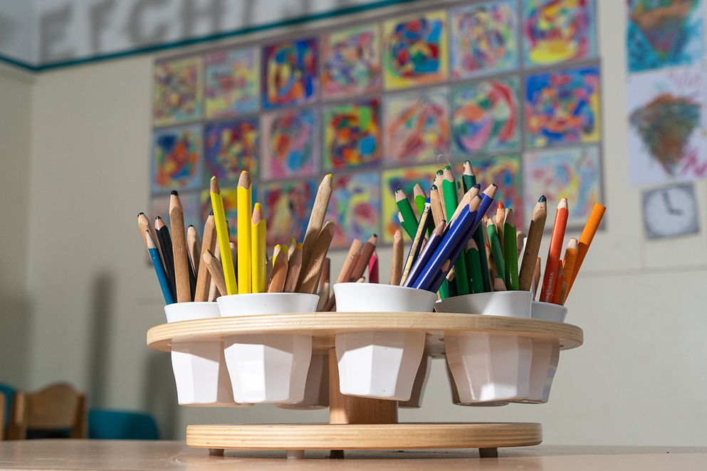 Stifte in Bechern in einem Klassenzimmer. 