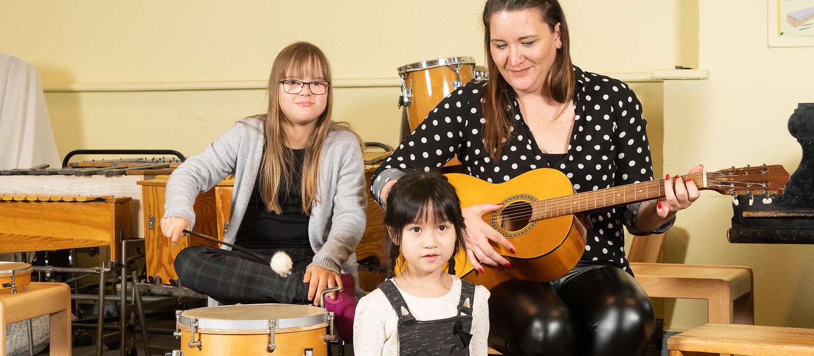 Eine Fachkraft mit zwei Kindern und Musikinstrumenten im Ganztag
