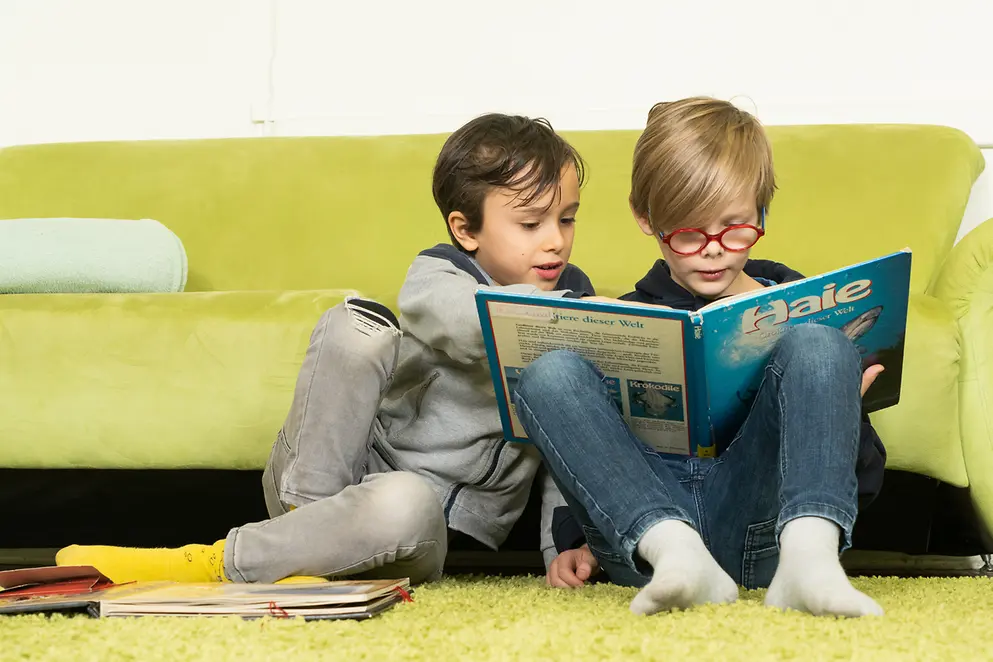 Das Bild zeigt zwei Kinder, die ein Buch lesen