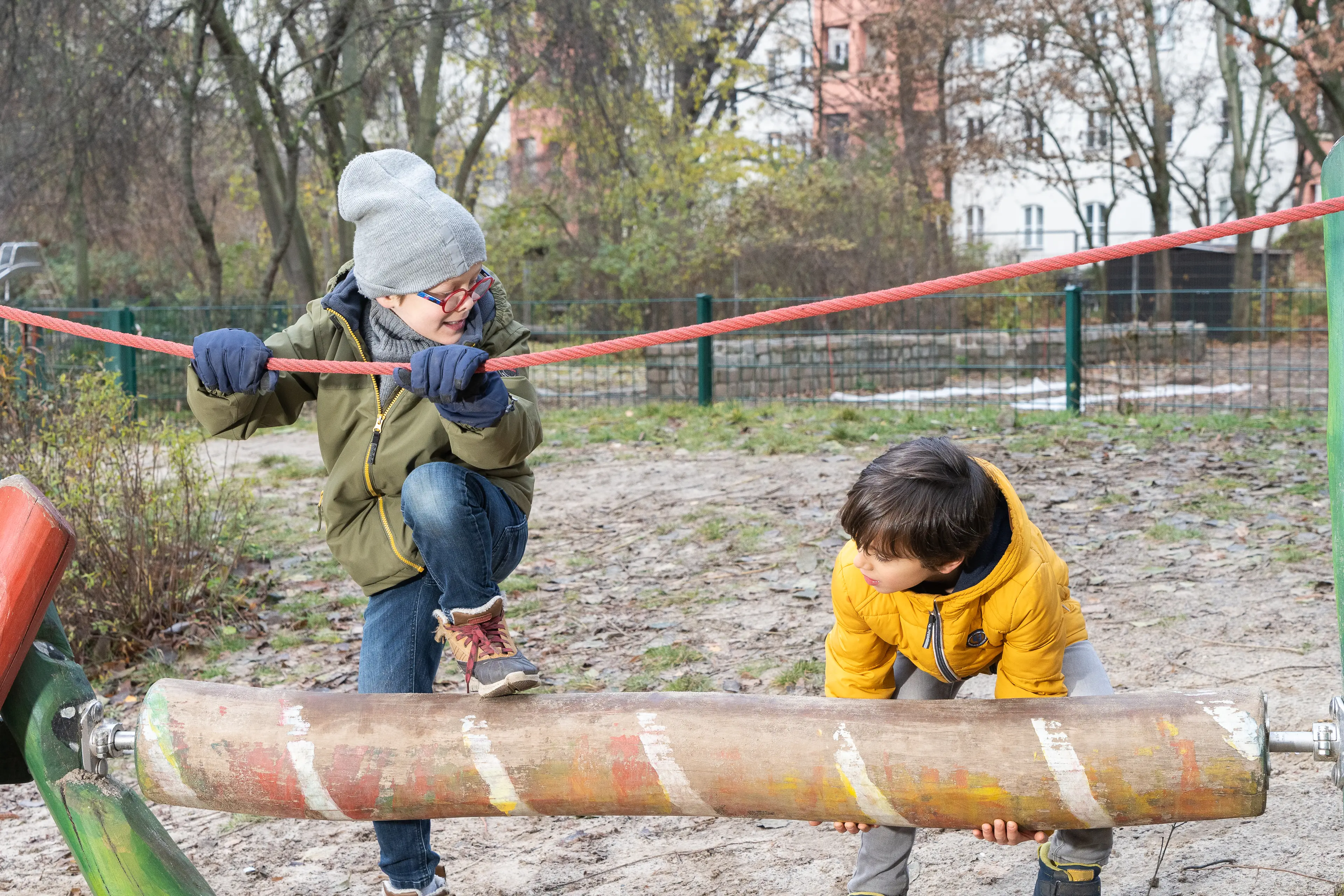 Zwei Kinder spielen auf einem Spielplatz.
